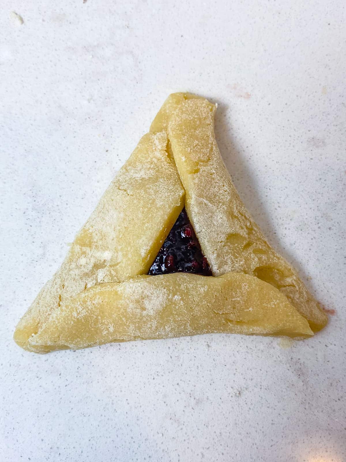 Fold the last side of the dough up, forming a hamantaschen cookies and gently pinch the corners to seal.