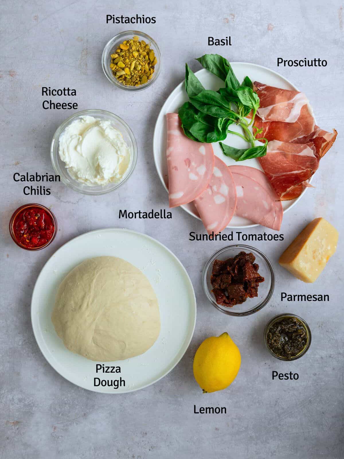 Ingredients for pizza dough sandwich, including fillings with ricotta cheese and meats, sundried tomatoes and pesto.