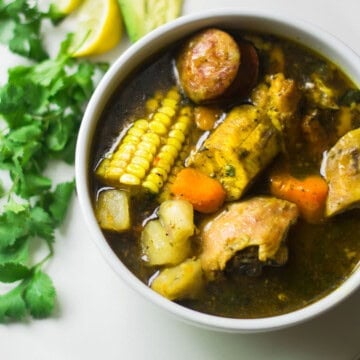Bowl of Dominican sancocho with corn, sausage and yucca.