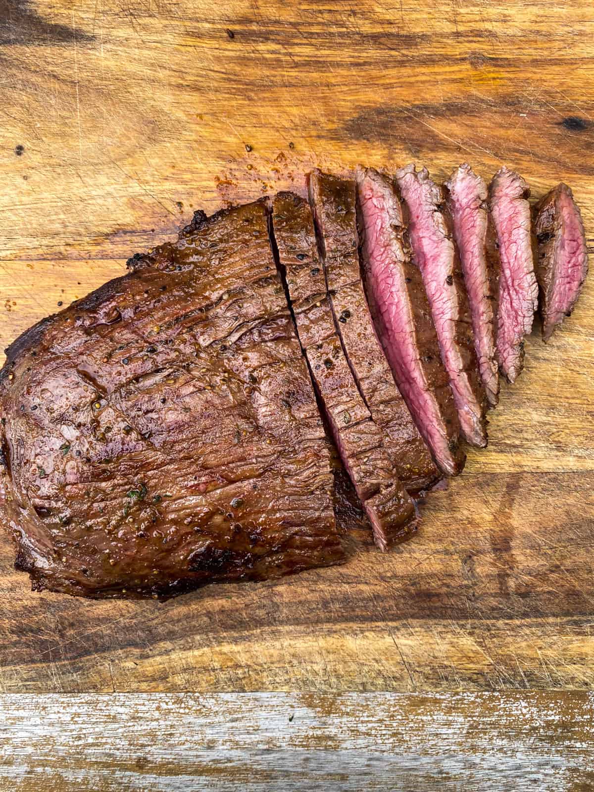 Slice the grilled flank steak against the grain into thin slices.