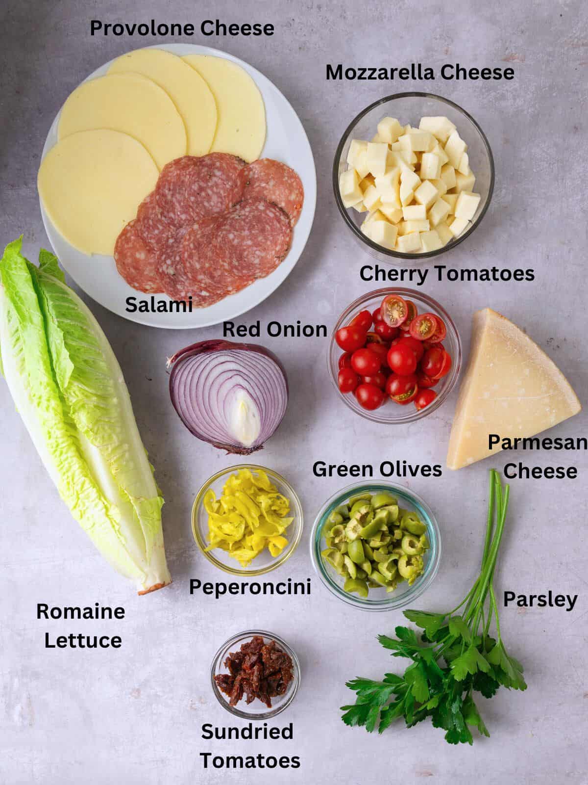 Ingredients for chopped antipasto salad including salami, provolone cheese, olives and sundried tomatoes.