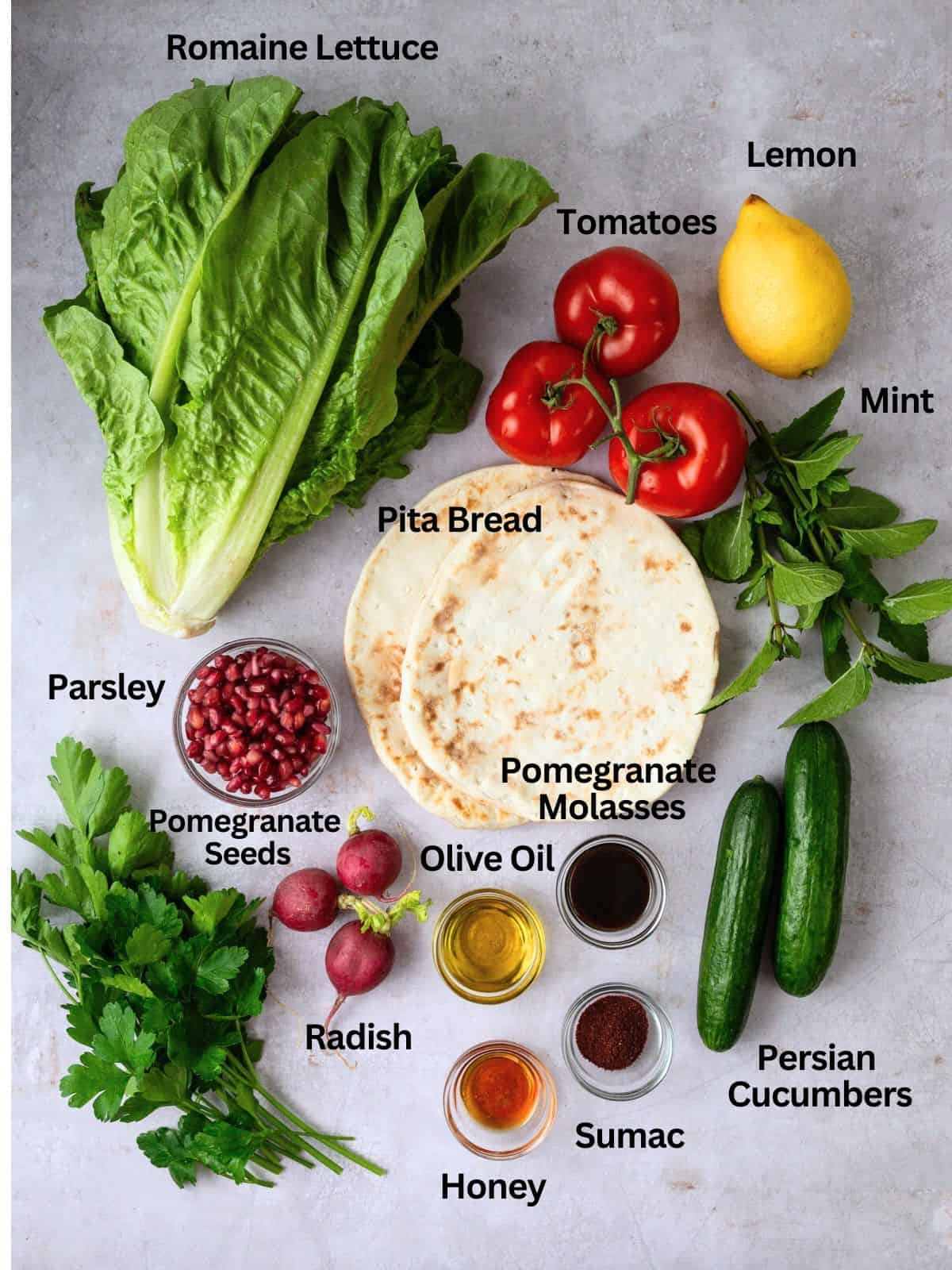 Ingredients for fattoush salad including cucumber, fresh herbs, pomegranate seeds and pomegranate molasses vinaigrette.