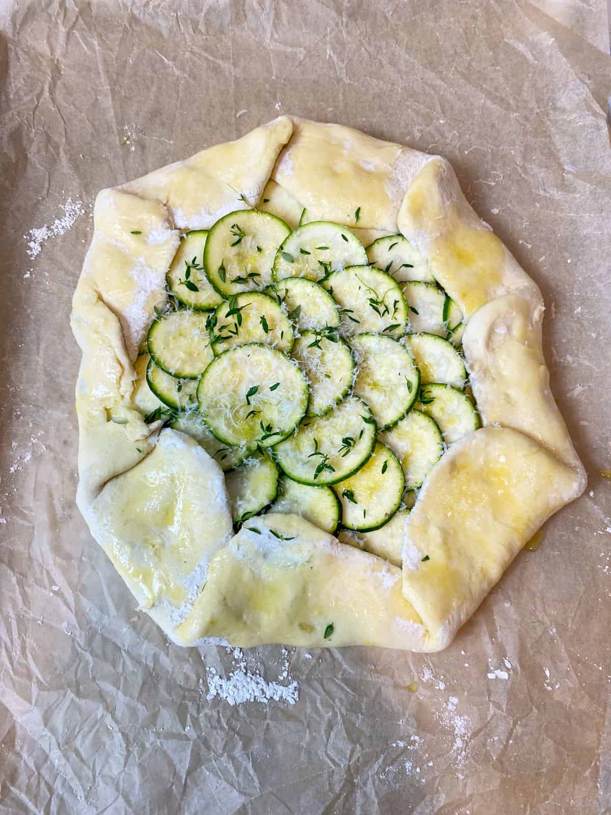 Form the zucchini galette and brush with olive oil and garnish with fresh thyme.