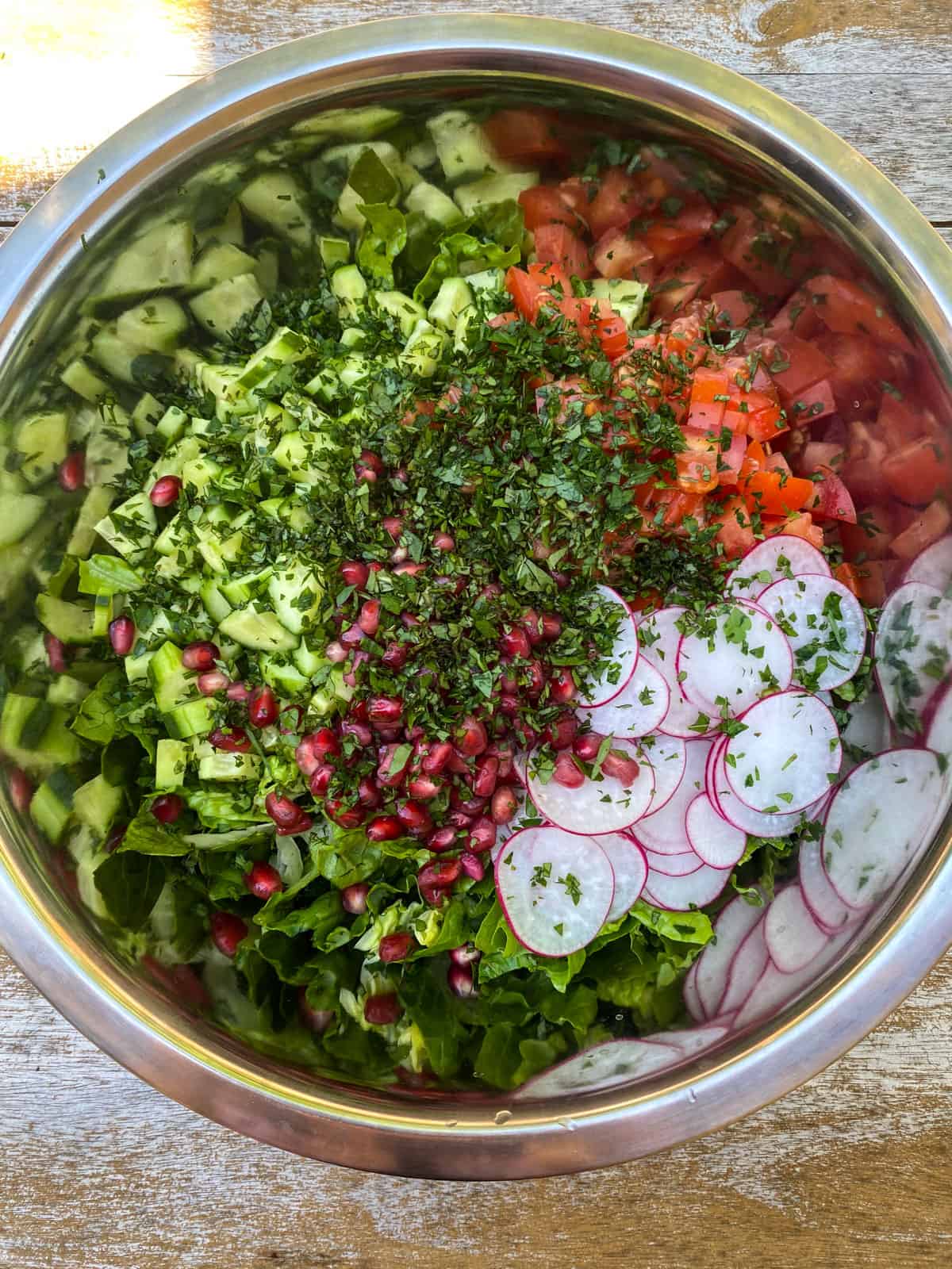 Layer the fattoush salad with the chopped vegetables, fresh herbs and pomegranate seeds.