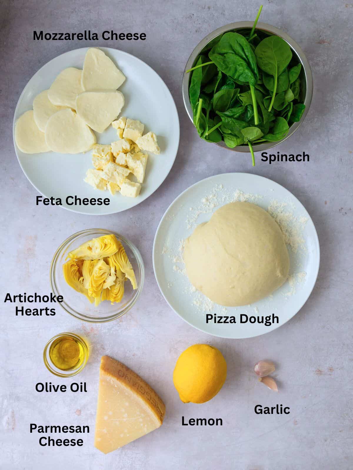 Ingredients for spinach and feta pizza including lemon, artichoke hearts and mozzarella cheese.