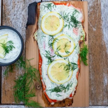 Grilled cedar plank salmon topped with a creamy dill sauce and lemon.