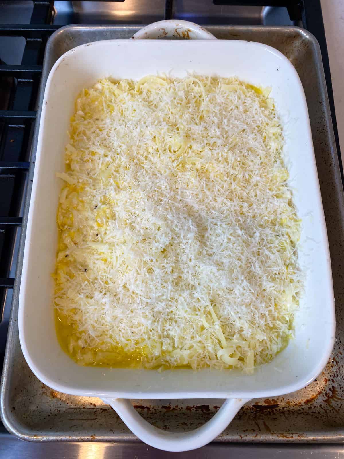 Add the squash and cheese mixture to an oiled casserole dish and top with grated Parmesan.