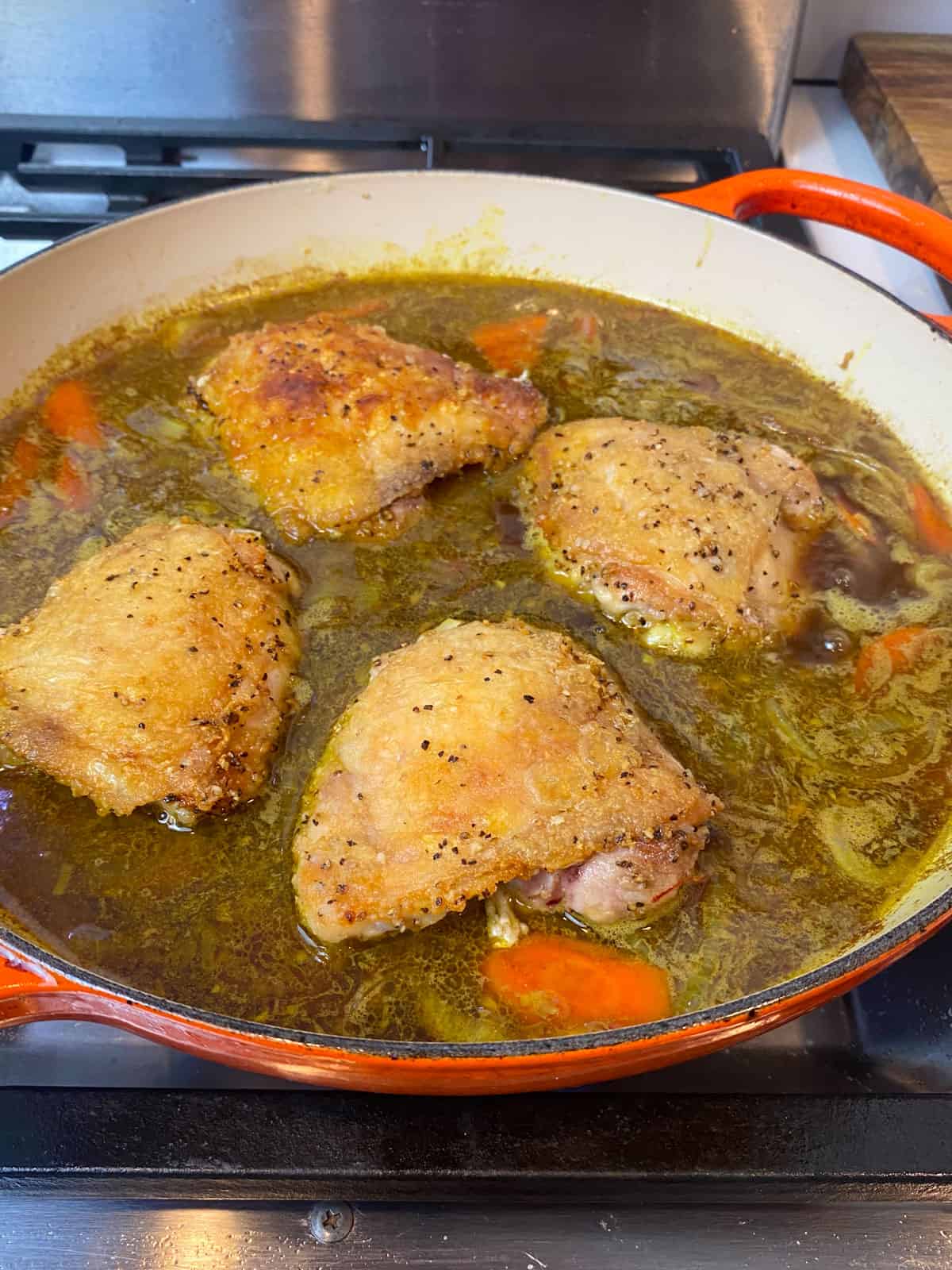 Add the seared chicken thighs back into the red wine braising liquid, skin side up.