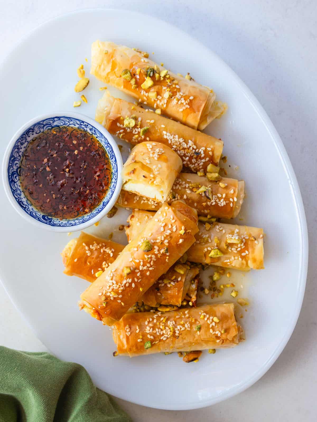 Phyllo feta rolls with sesame seeds and pistachios served with honey for dipping.