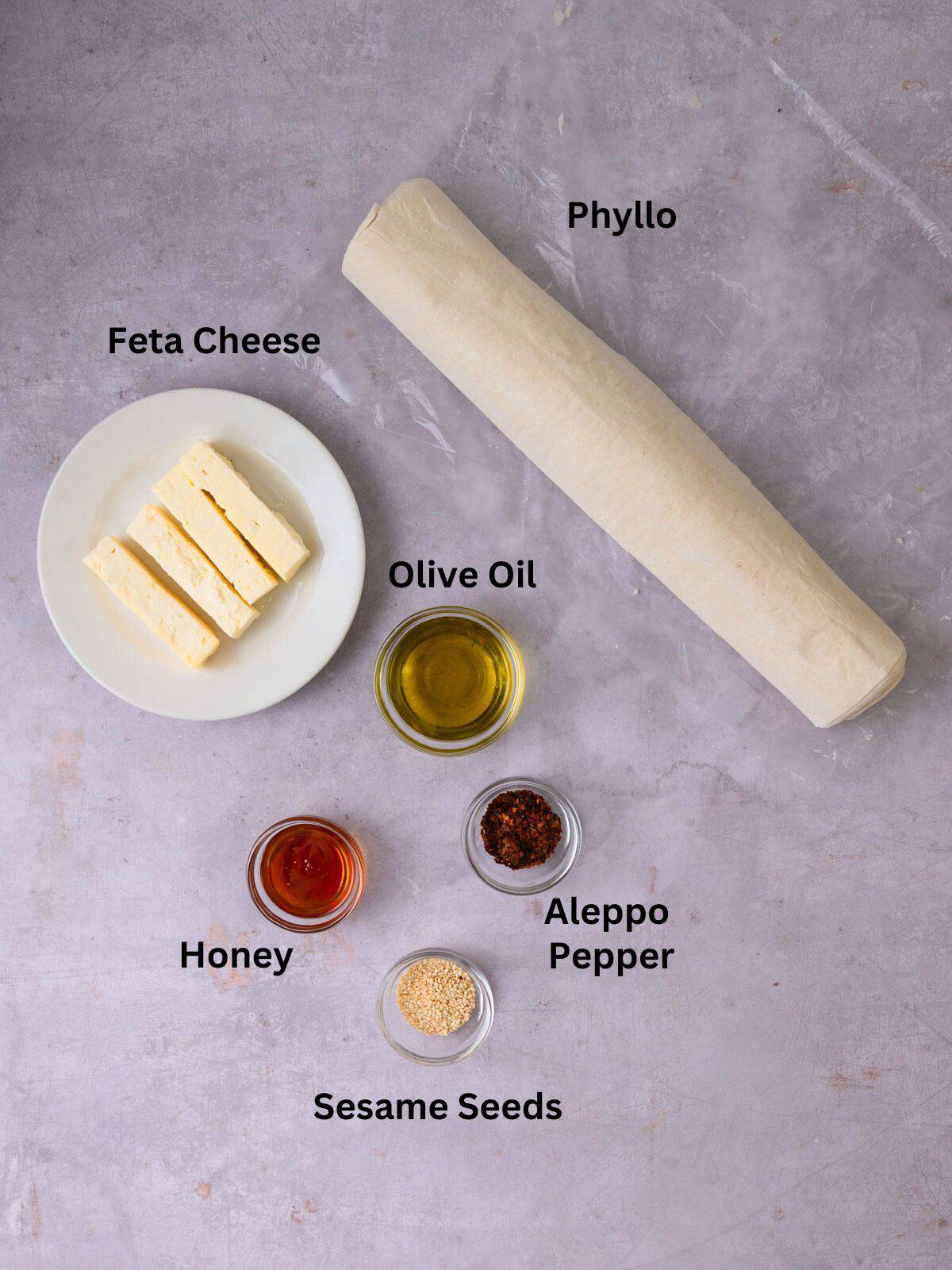 Ingredients for feta phyllo rolls, including olive oil, honey and feta cheese.