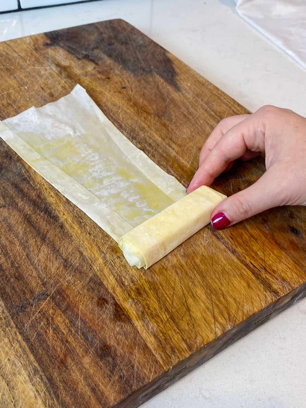 Roll up the feta cheese into the phyllo sheet, tucking in the sides.