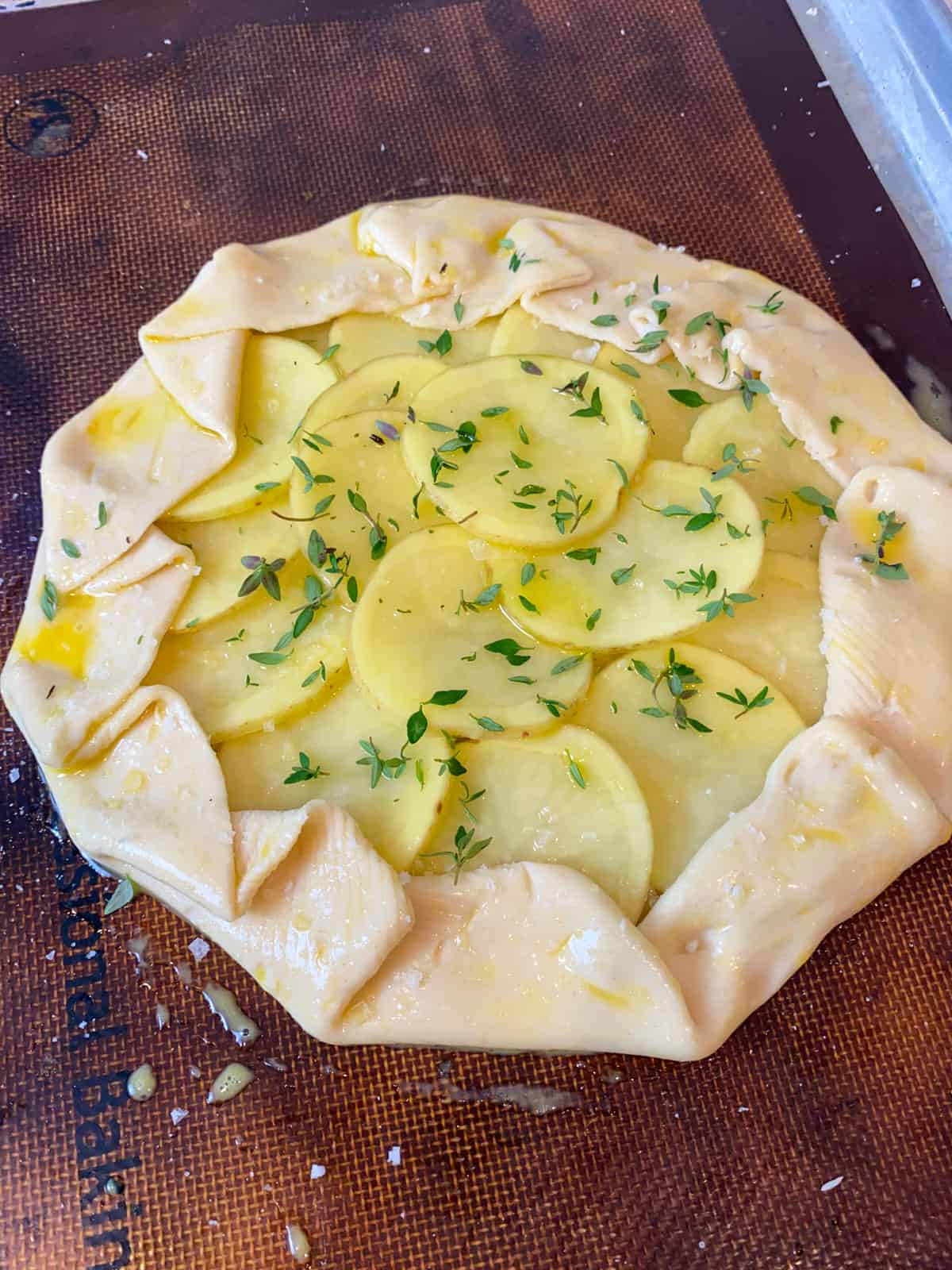 Fold pie dough around, creating a crust and brush with egg wash and sprinkle of thyme.