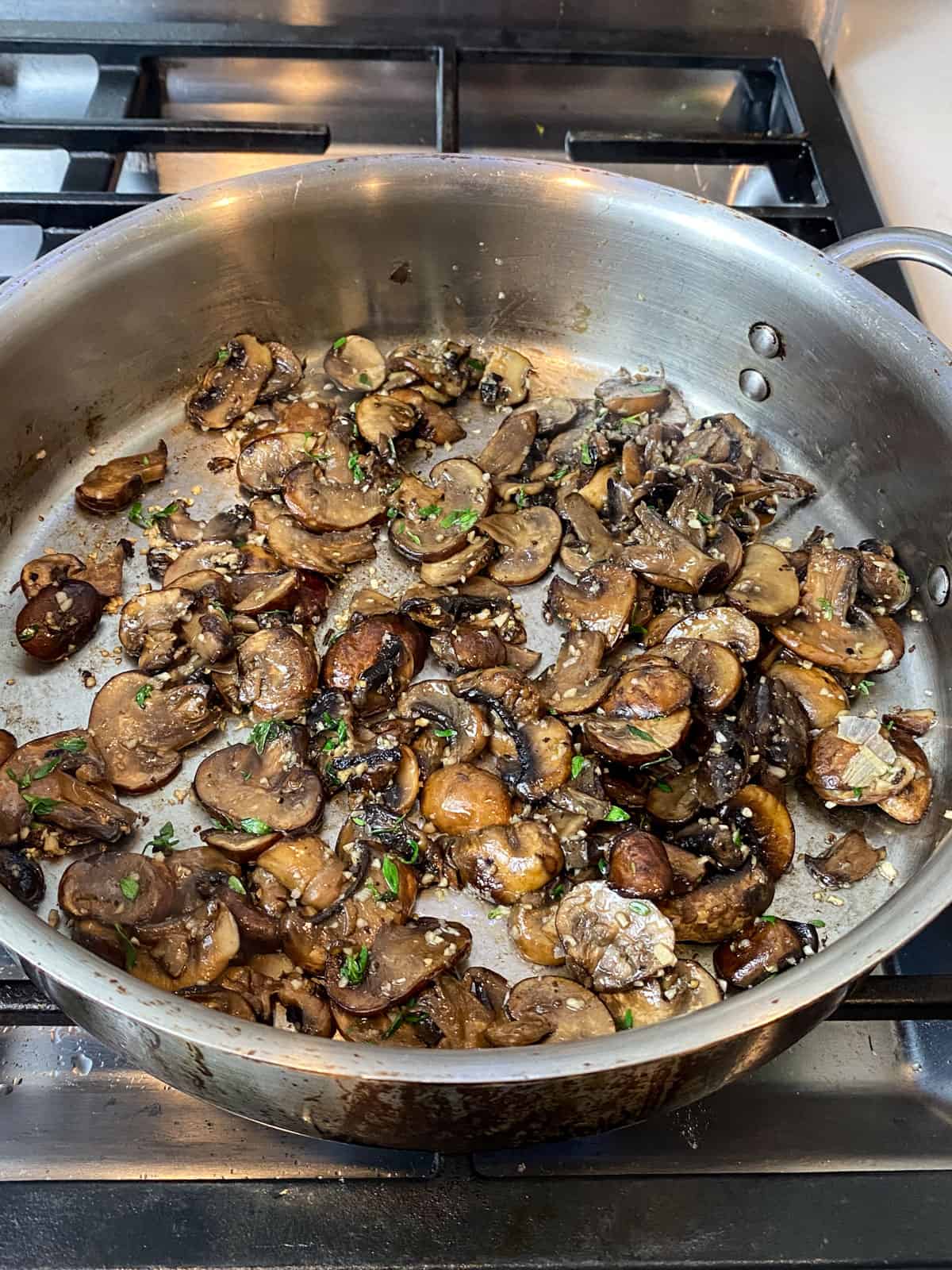 Add chopped garlic and thyme to the sautéed mushrooms.