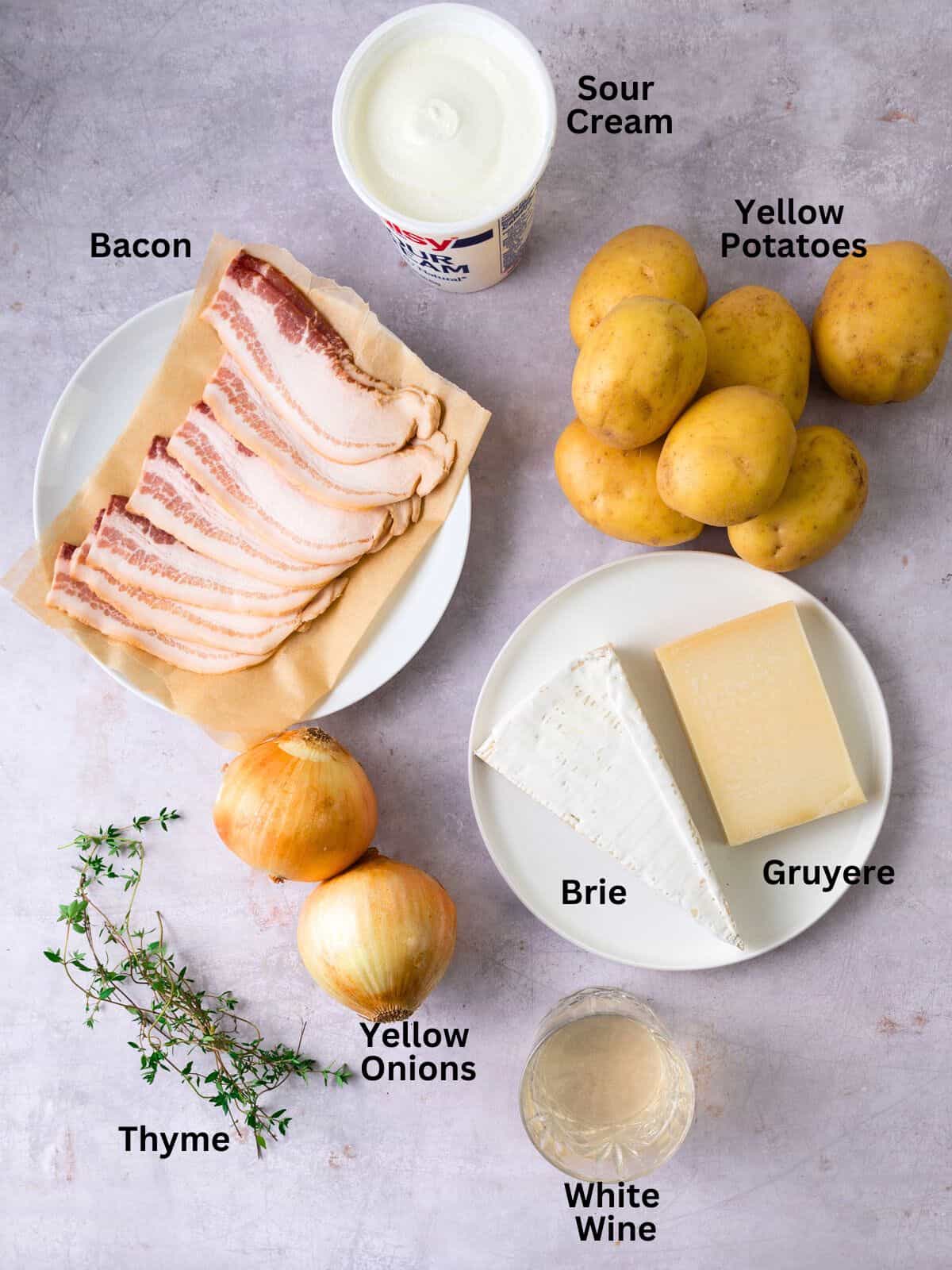 Ingredients for Tartiflette, a French potato casserole including bacon, onions, brie cheese and white wine.