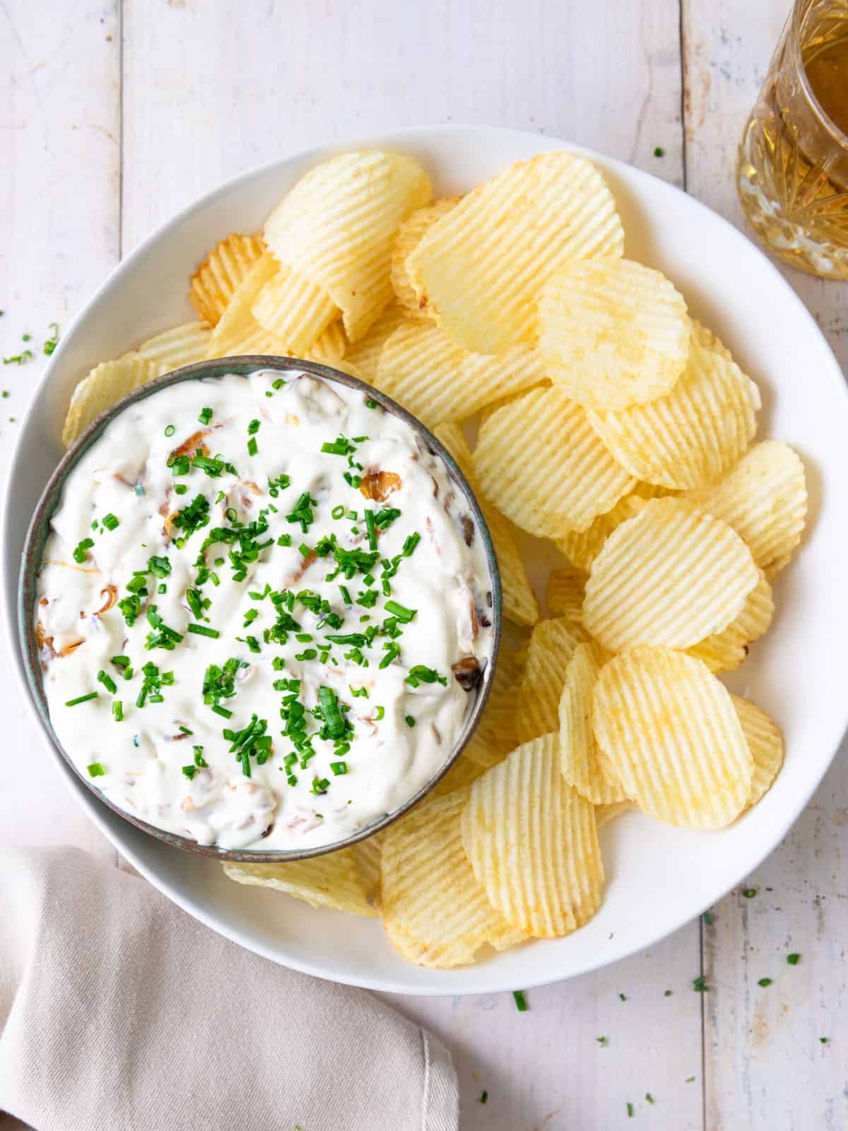 Homemade caramelized onion dip garnished with chives and served with potato chips.