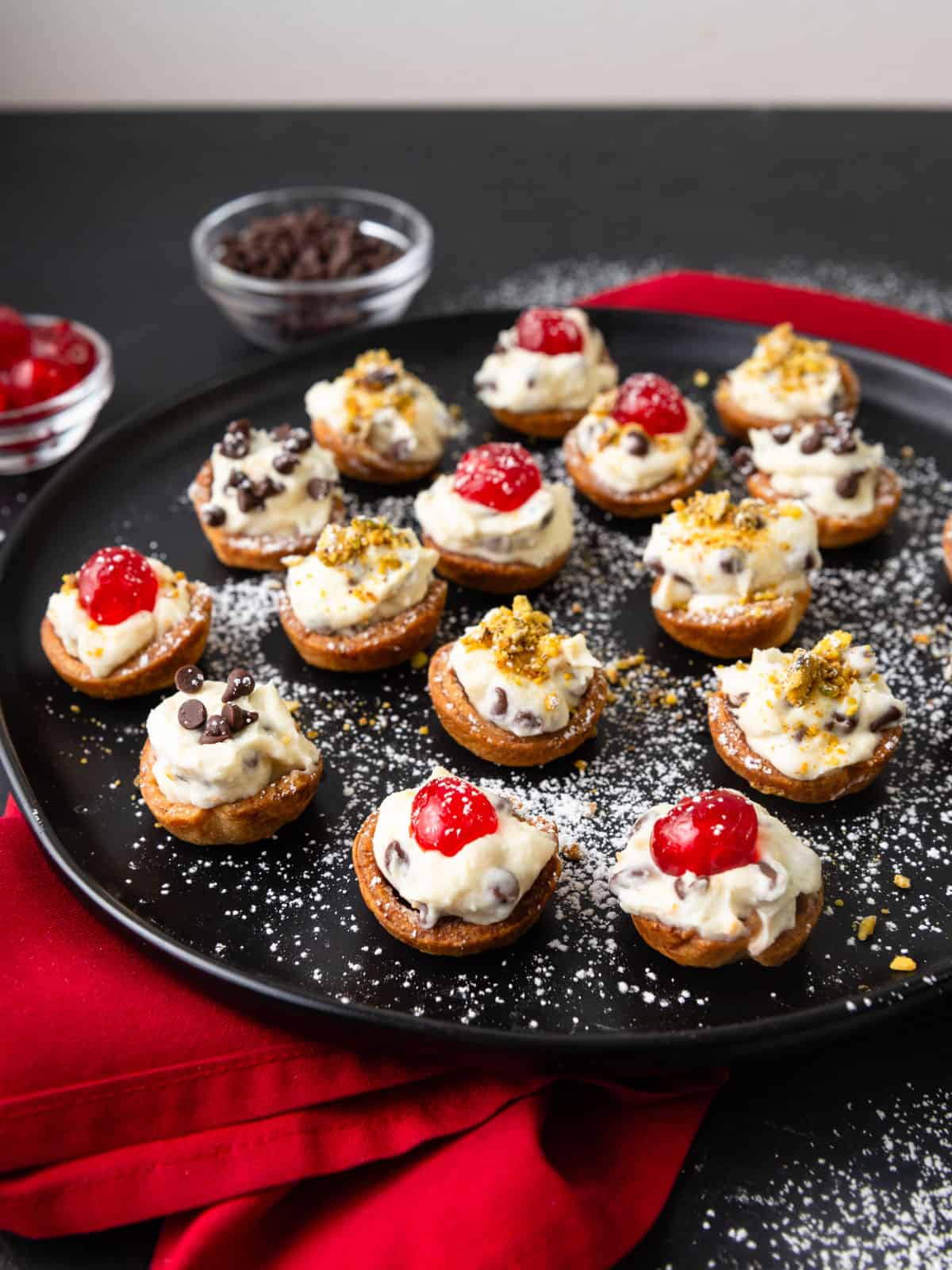 Mini cannoli cups filled with mascarpone cream and garnished with chocolate chips, candied cherries and pistachios.