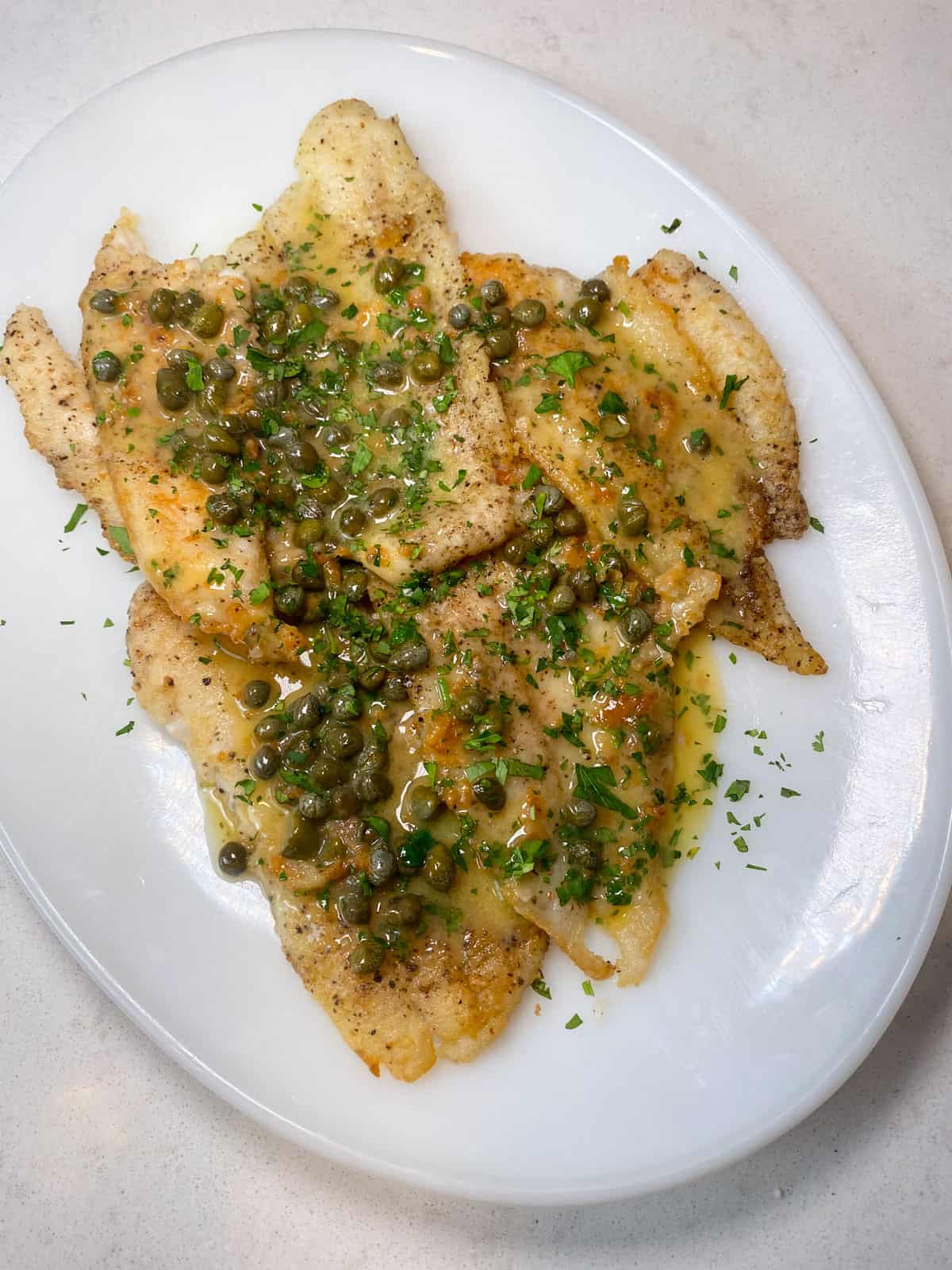 Pour the lemon caper sauce over the cooked sole fillets.