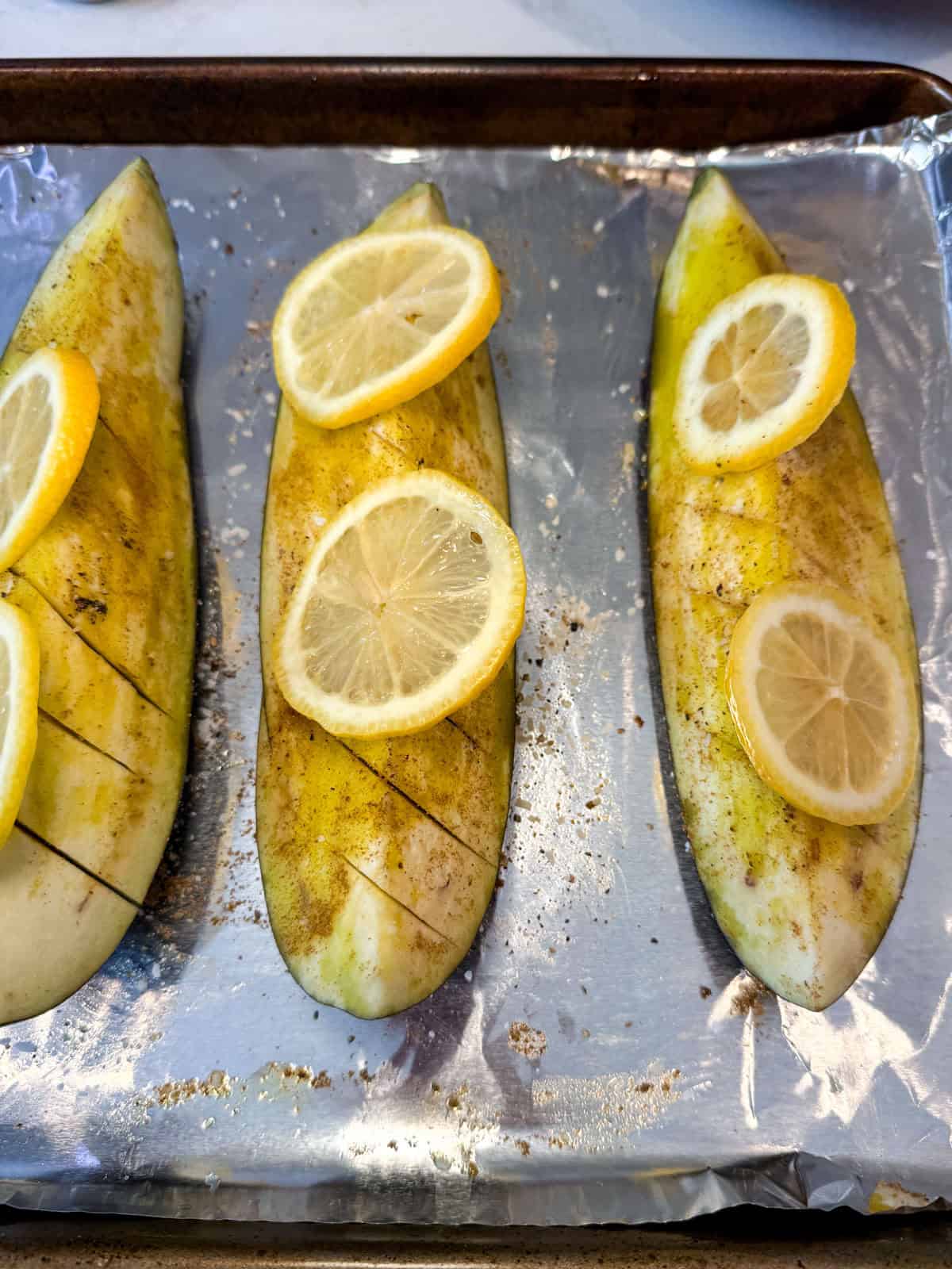 Brush olive oil onto the eggplant and season with cumin, coriander and top with lemon slices.