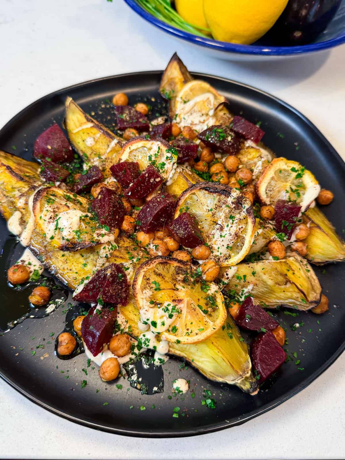 Serve the roasted eggplant on a platter and garnish with za'atar, sumac, tahini and roasted chickpeas.