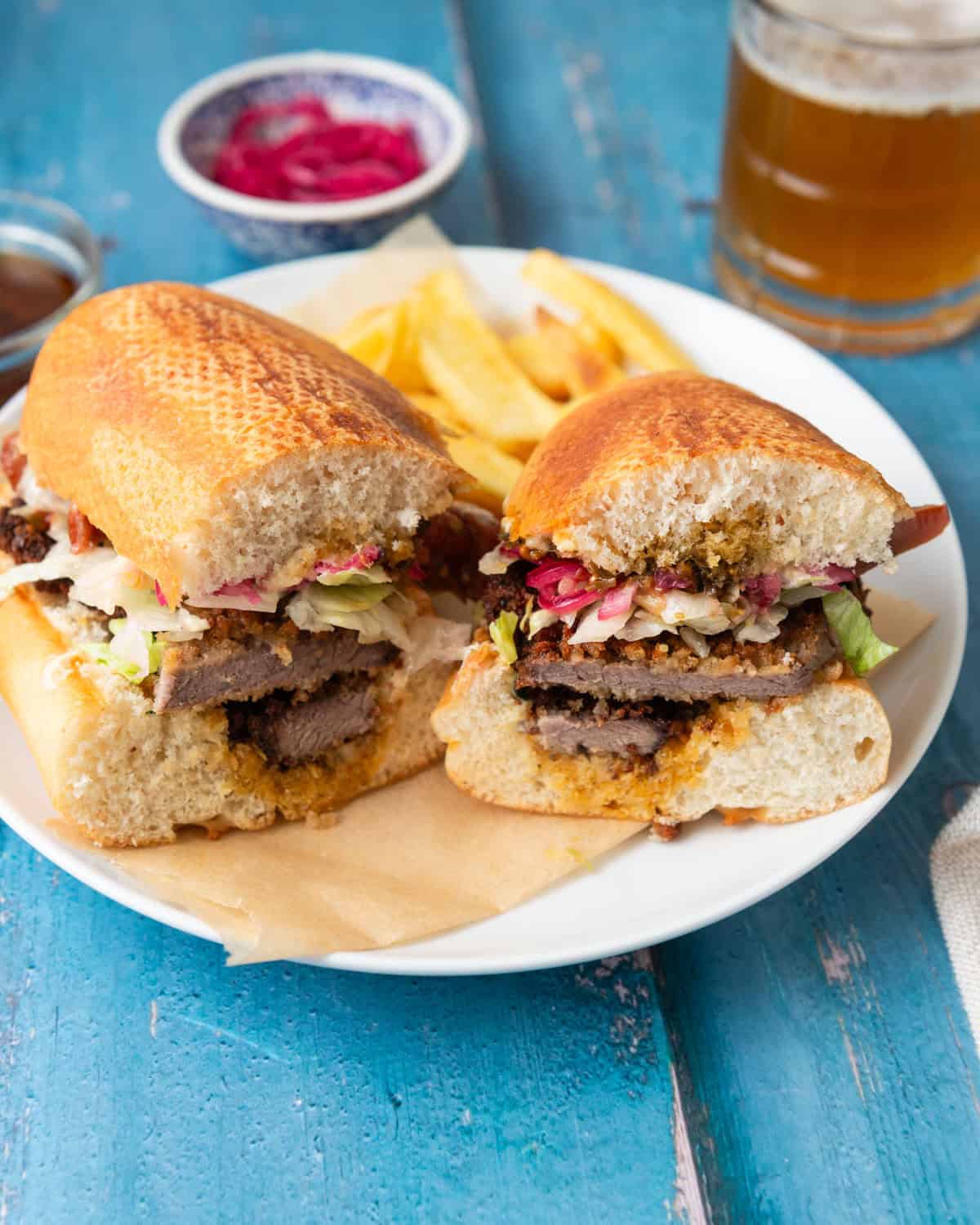 Argentinian beef milanesa sandwich is layered with chimichurri, pickled onions and fresh veggies.