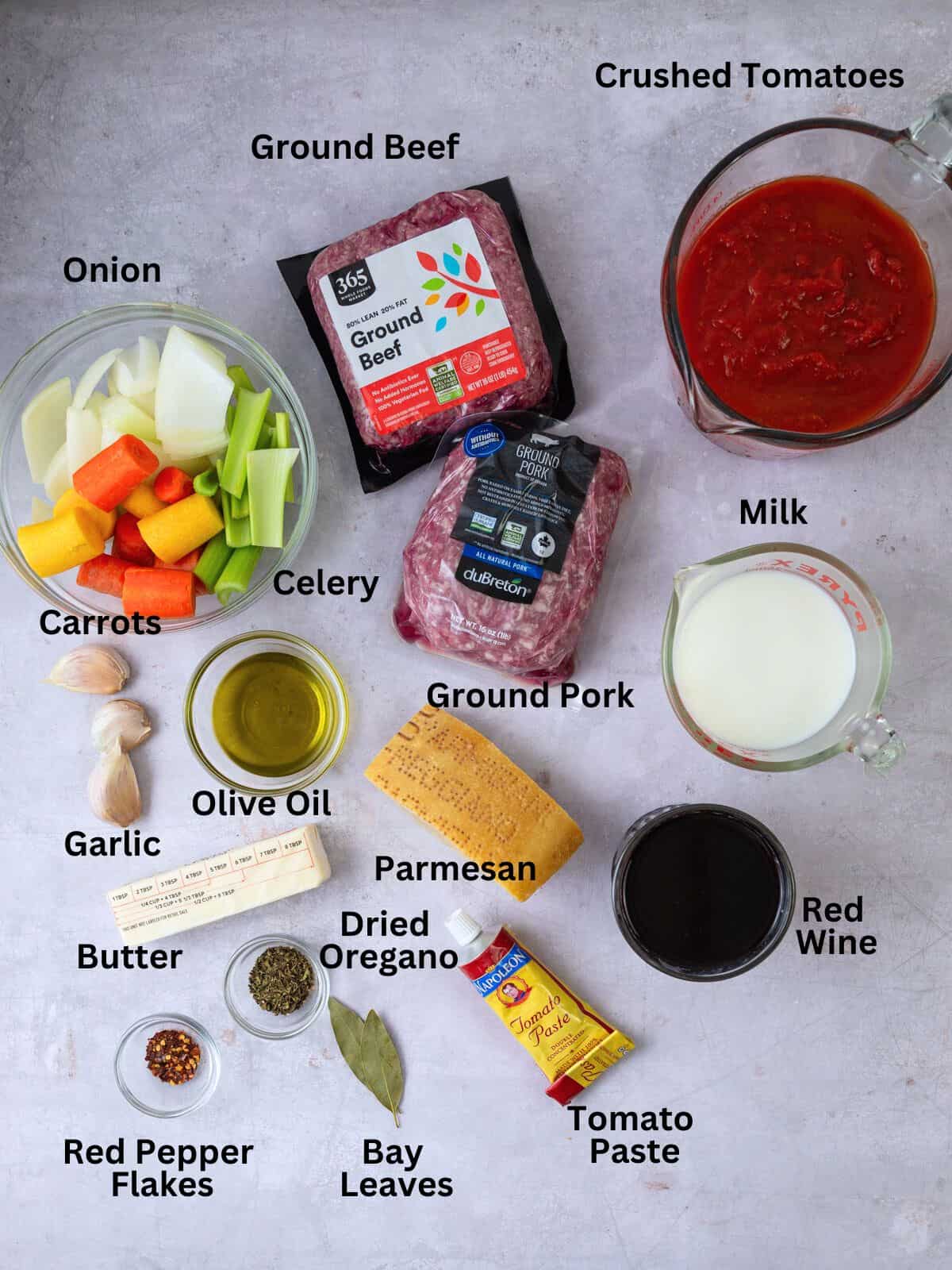 Ingredients for bolognese sauce including ground pork, ground beef, red wine, milk and vegetables.