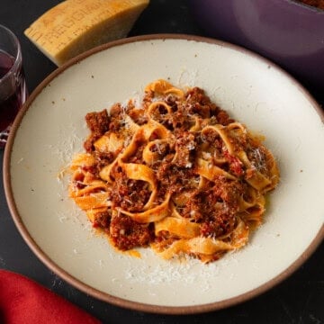 Bolognese sauce recipe with pasta and topped with grated Parmesan cheese.