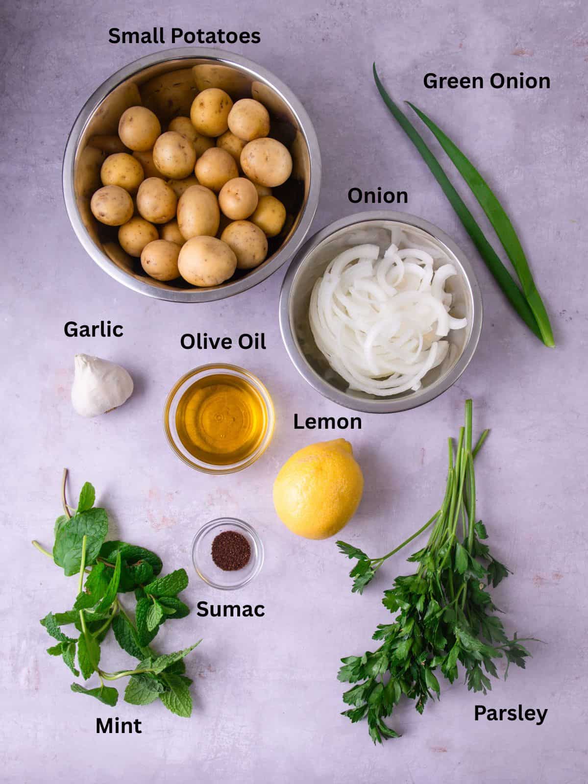 Ingredients for Lebanese potato salad including thinly sliced onions, fresh min, parsley, olive oil and sumac.