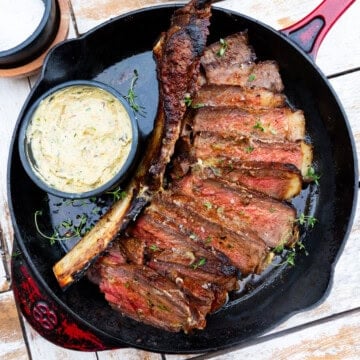 Seared tomahawk steak with charred shallot compound butter and thyme.