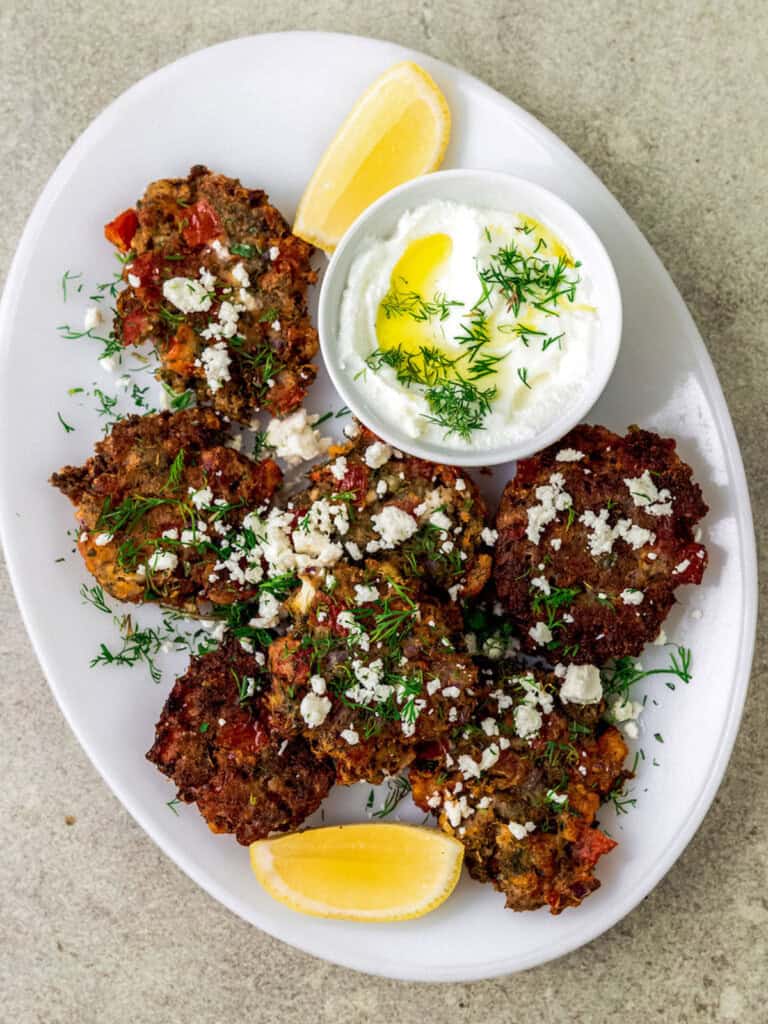 Greek tomato fritters are savory pancakes that are full of sweet tomatoes, fresh mint, dill and creamy feta cheese. The tomato fritters is fried until perfectly golden brown on both sides and served with a bright and lemony yogurt dill sauce.
