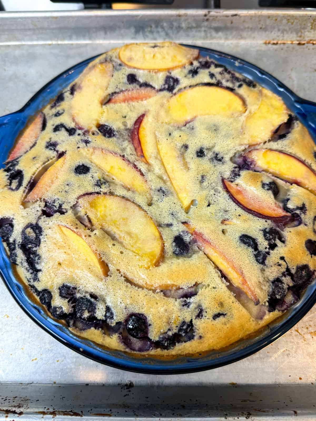 Bake the peach and blueberry clafoutis until it puffs up.