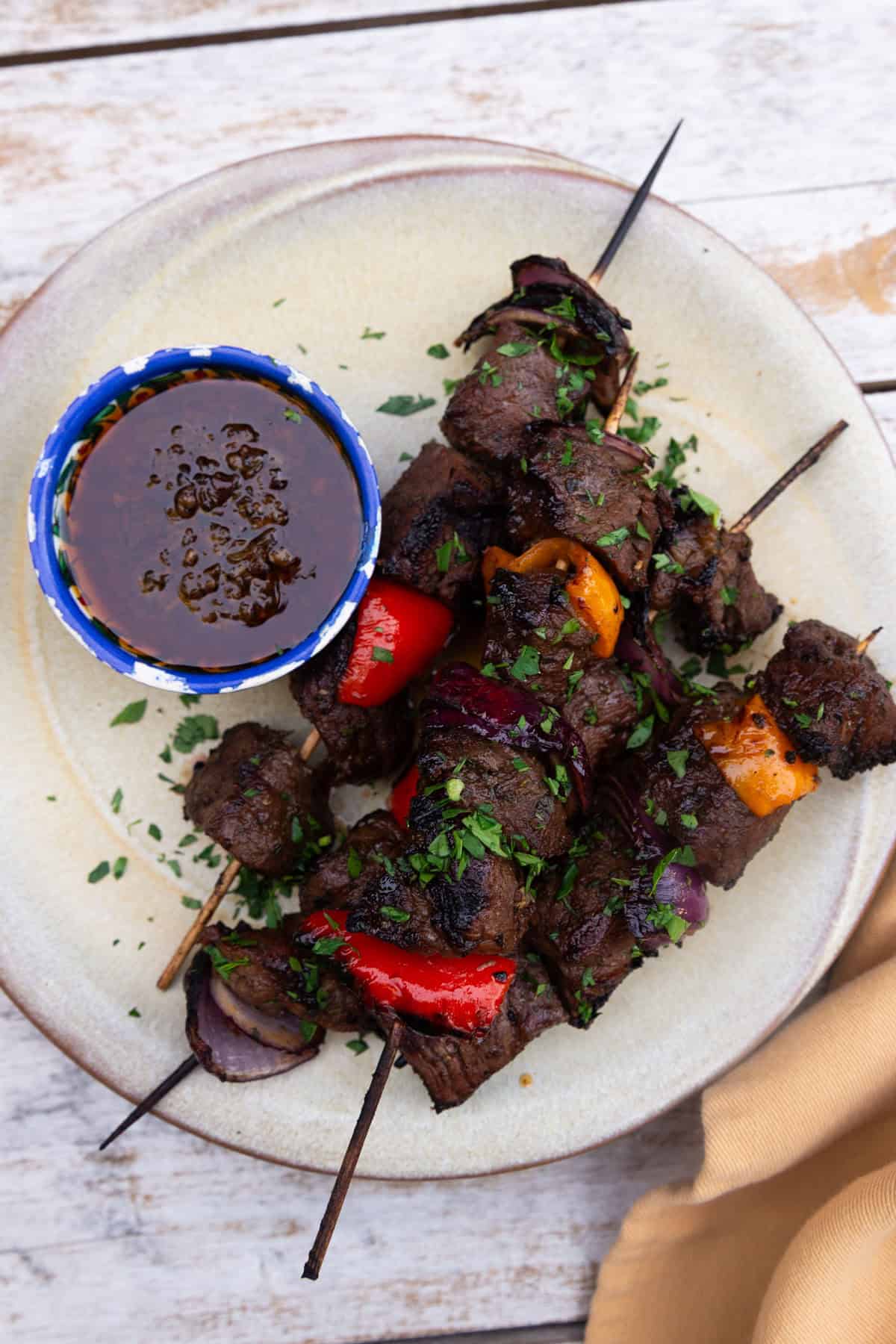 Balsamic beef kabobs with vegetables and served with chimichurri.
