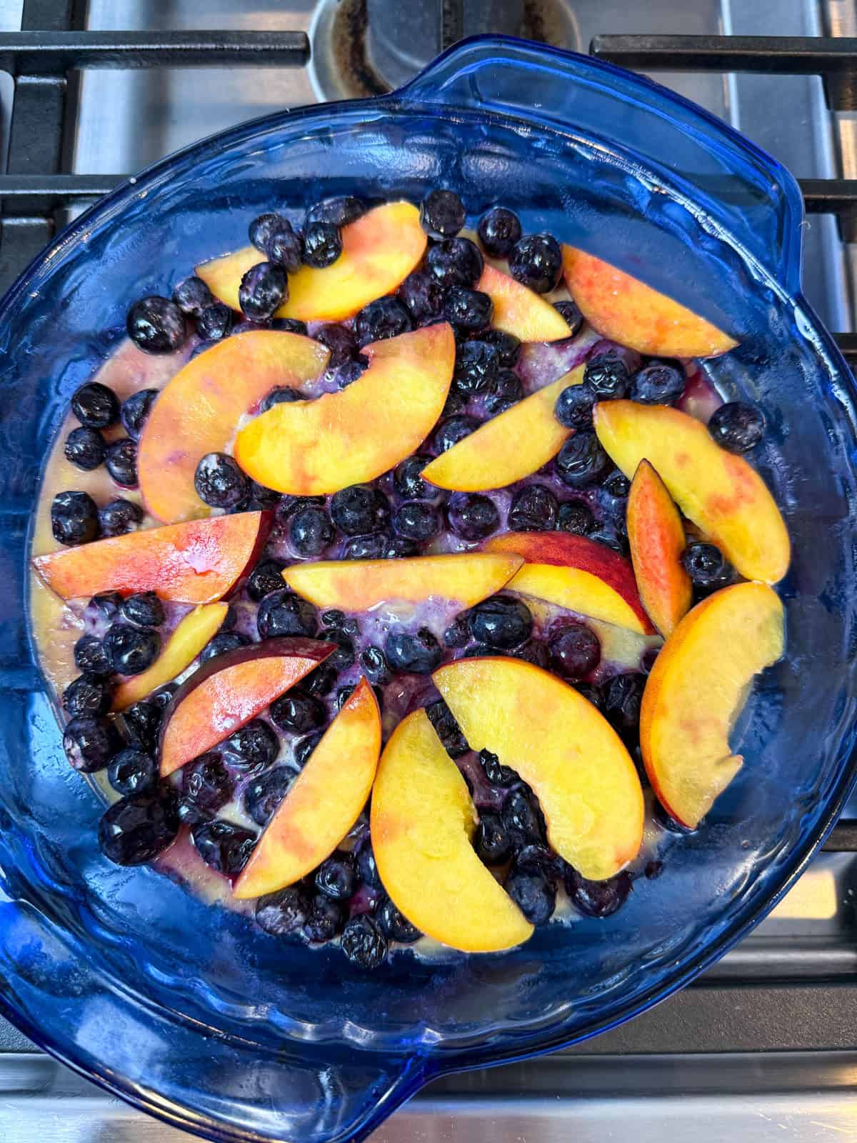 Lay the blueberries and sliced peaches on top of the par-baked clafoutis batter.