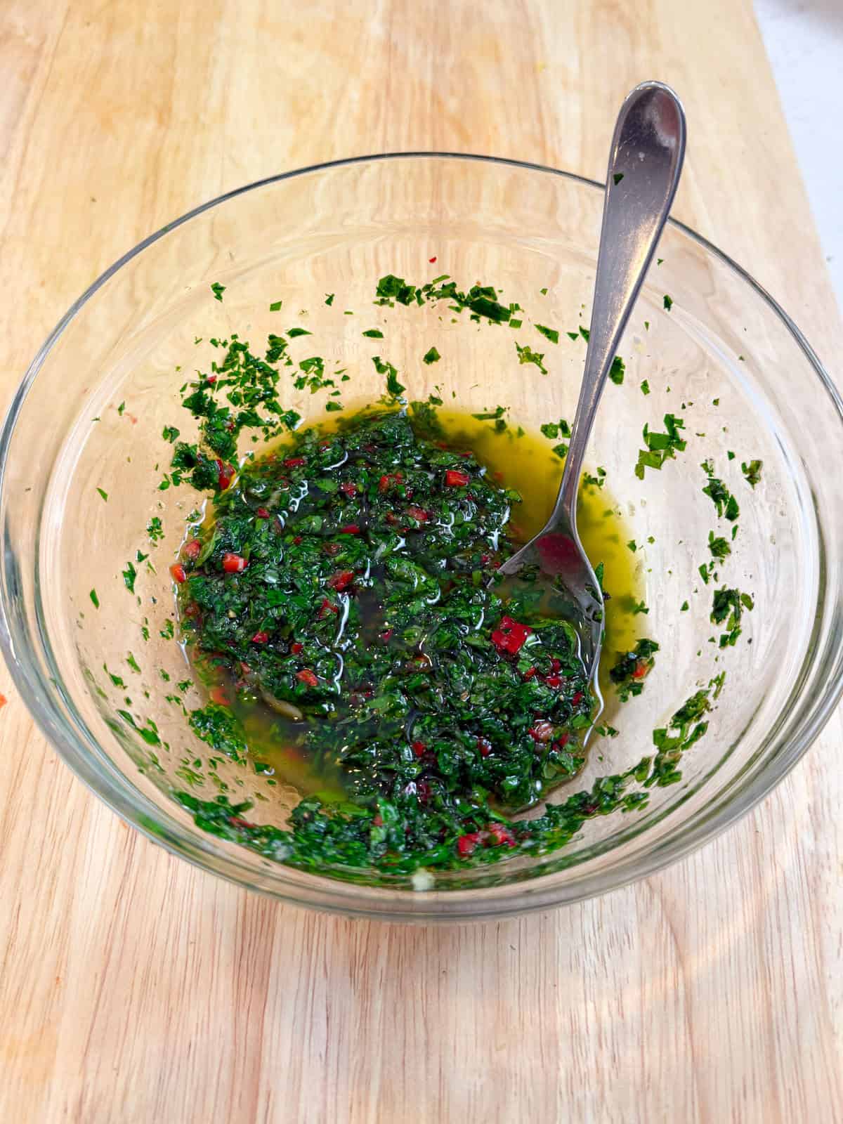 Add the fresh herbs, chopped garlic and Fresno chile to a bowl with olive oil and a splash of red wine vinegar and mix together for the chimichurri.