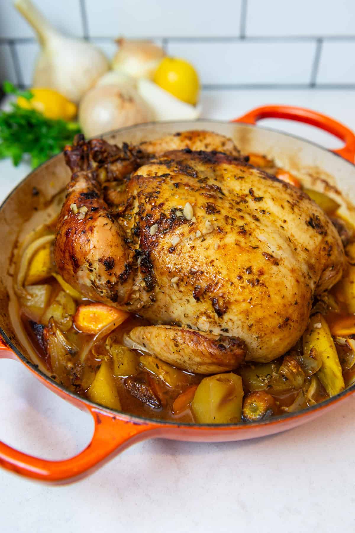 Dutch oven roast chicken seasoned with a flavorful herb compound butter and roasted vegetables.