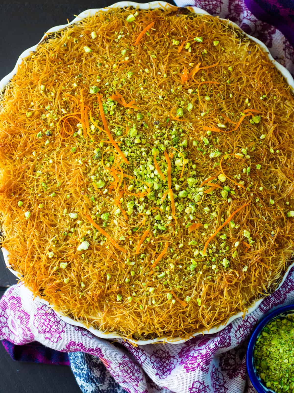 Kanafe topped with chopped pistachios and orange blossom water.