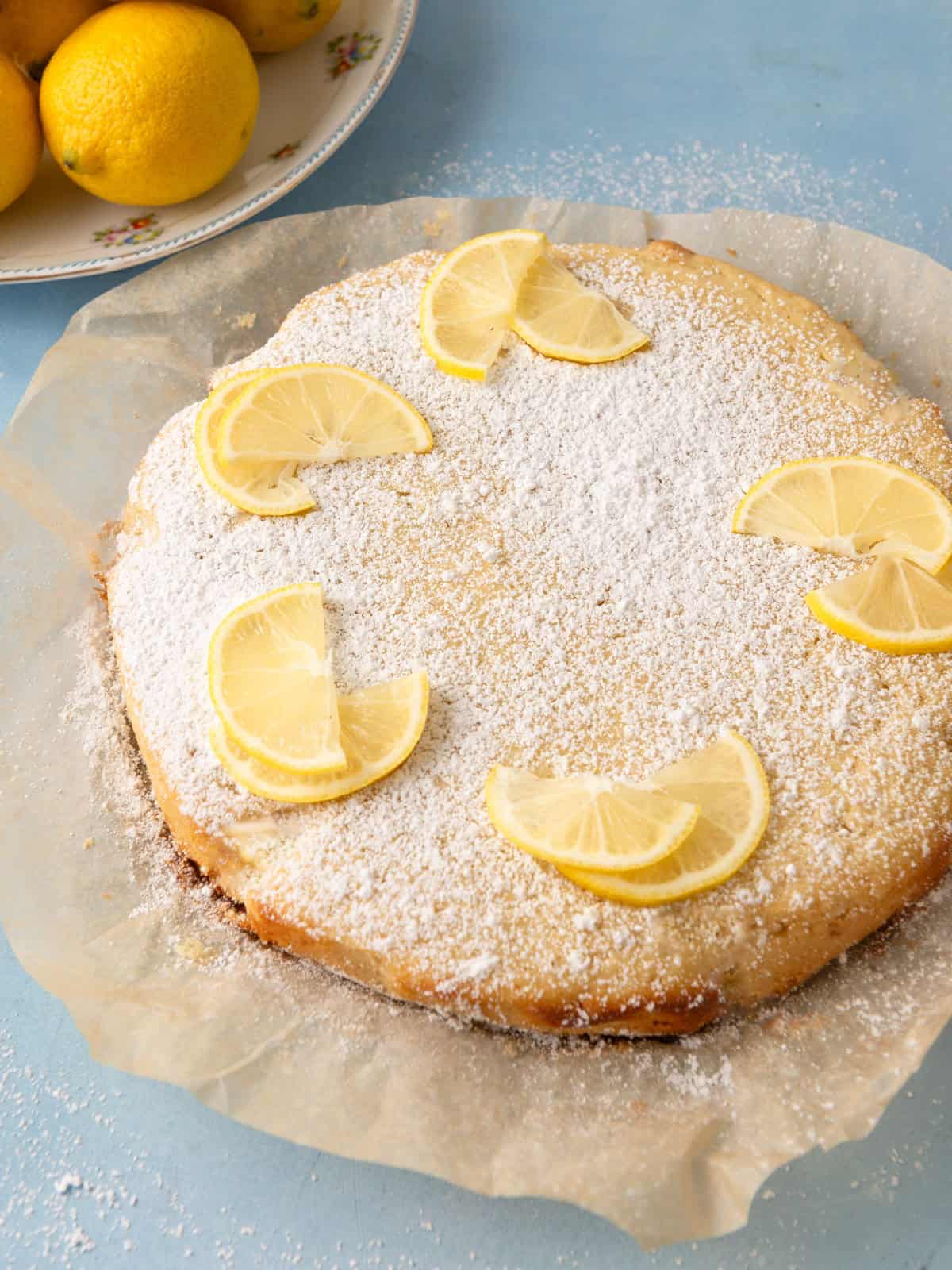 Garnish the lemon olive oil cake with powdered sugar and lemon slices.