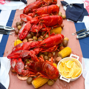 Lobster boil party with whole Main lobsters over boiled potatoes, corn and sausage.