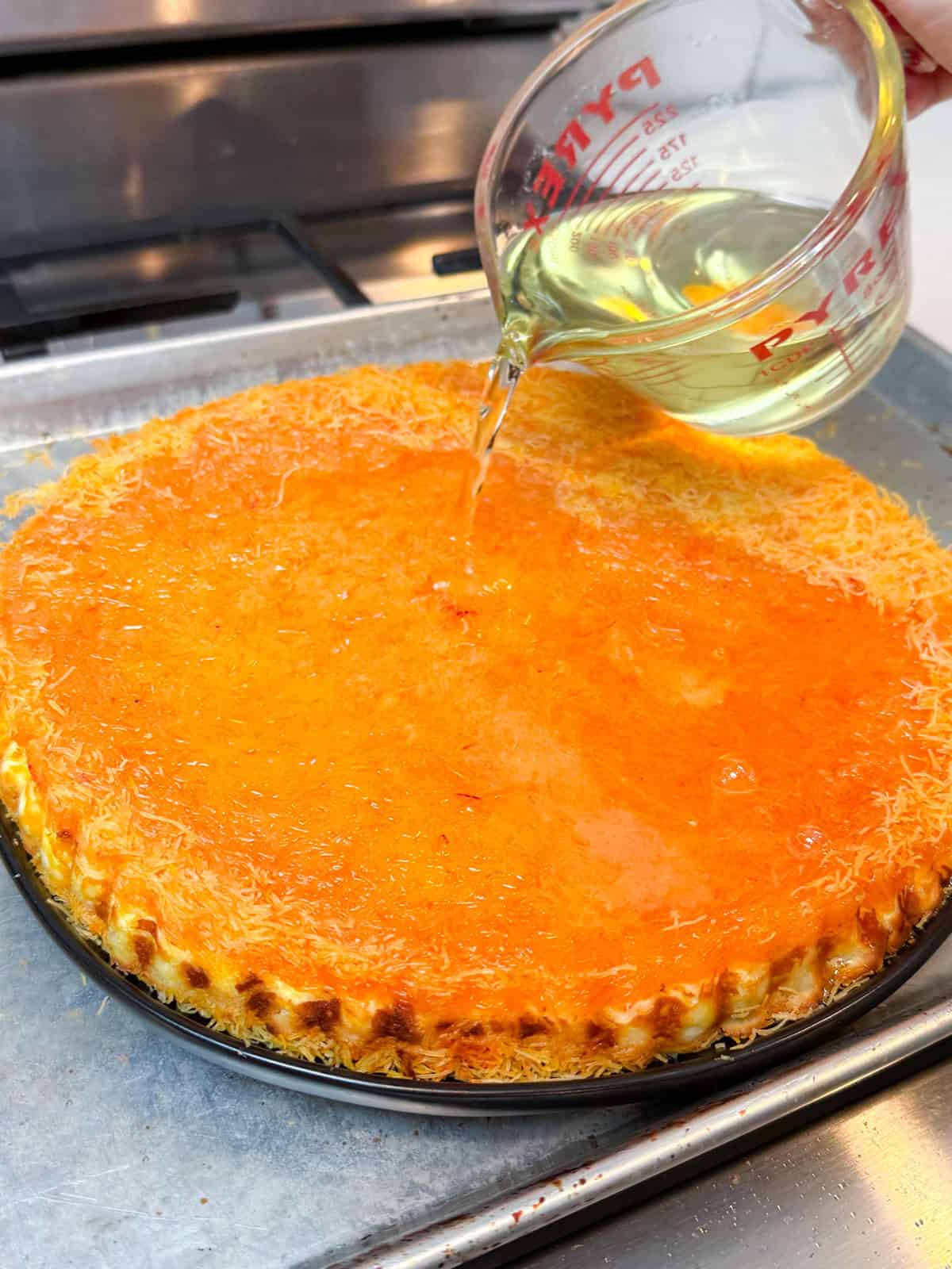 Pour the orange blossom simple syrup on top of the baked kanafe.