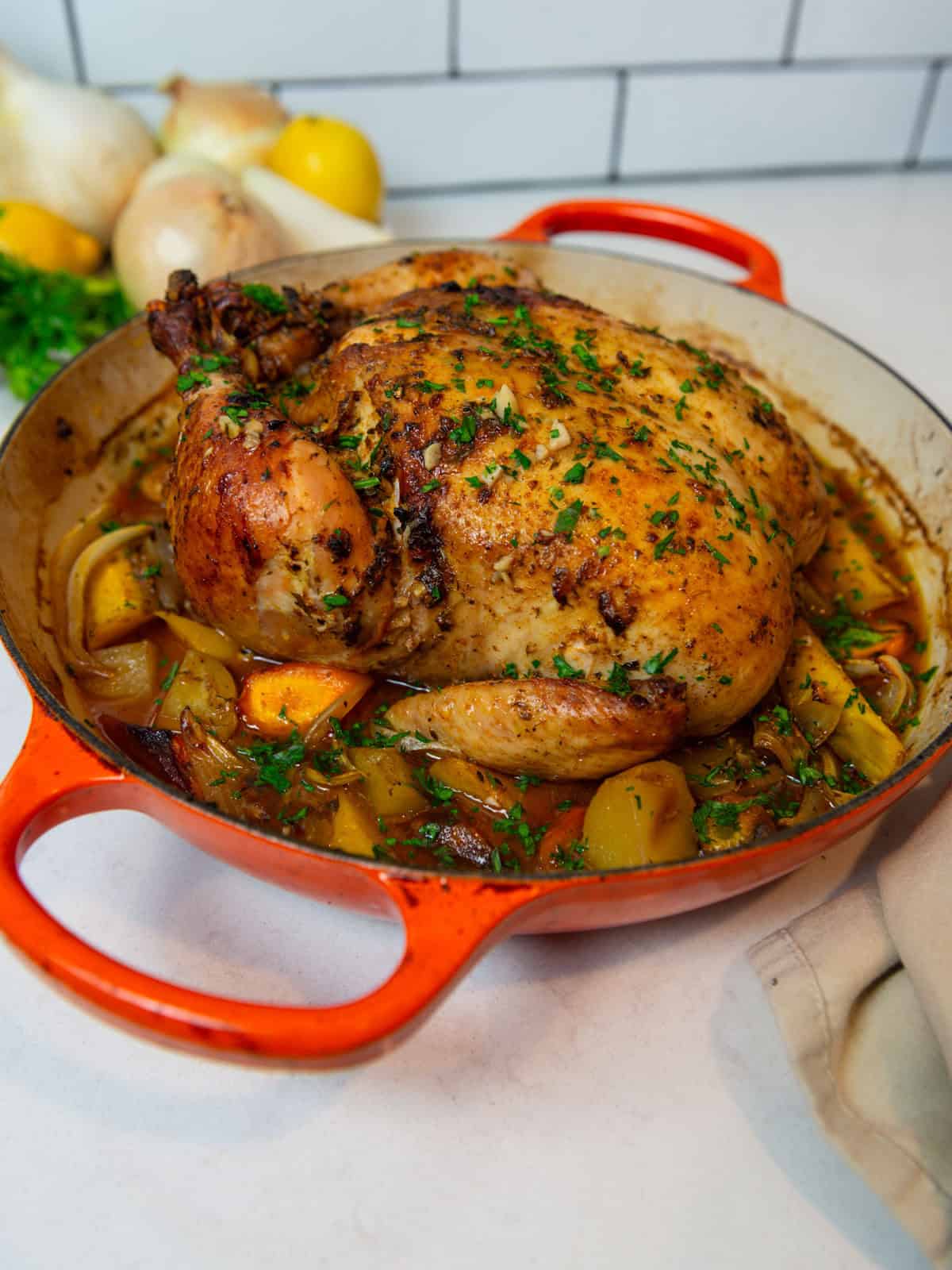 Whole roasted chicken in Dutch oven with roasted vegetables.