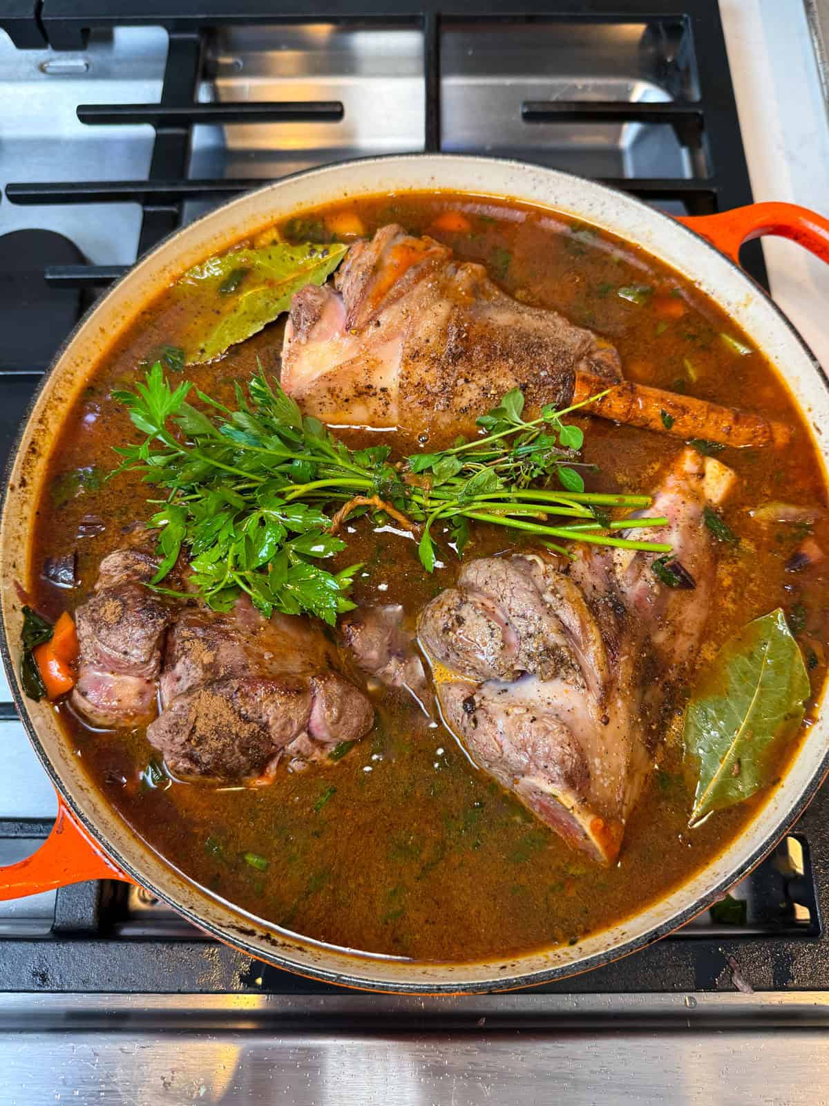 Add herbs and stock to the seared lamb shanks and simmer until lamb is tender.