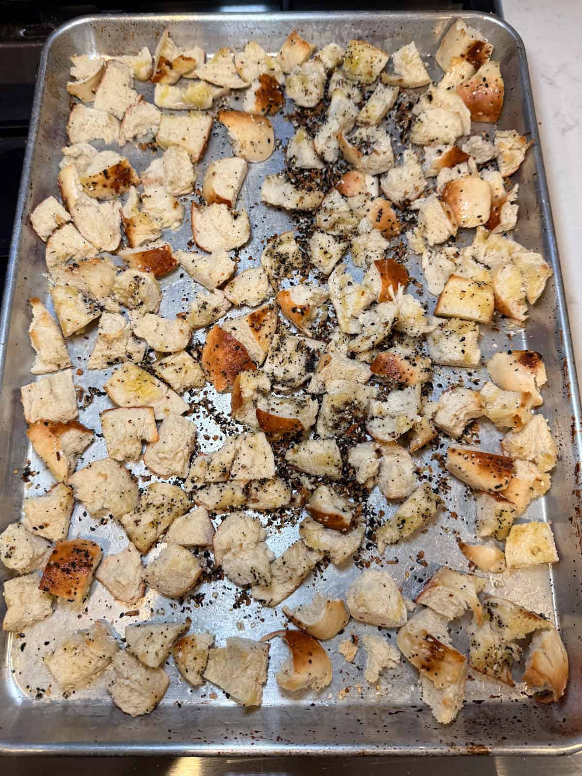 Season the torn bagel cubes with everything bagel spice and toast to dry the bread out.
