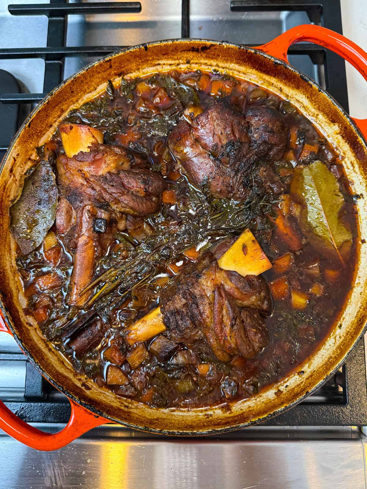 Cook the red wine braised lamb shanks in the oven until the lamb is tender and sauce has reduced, about 2 hours.