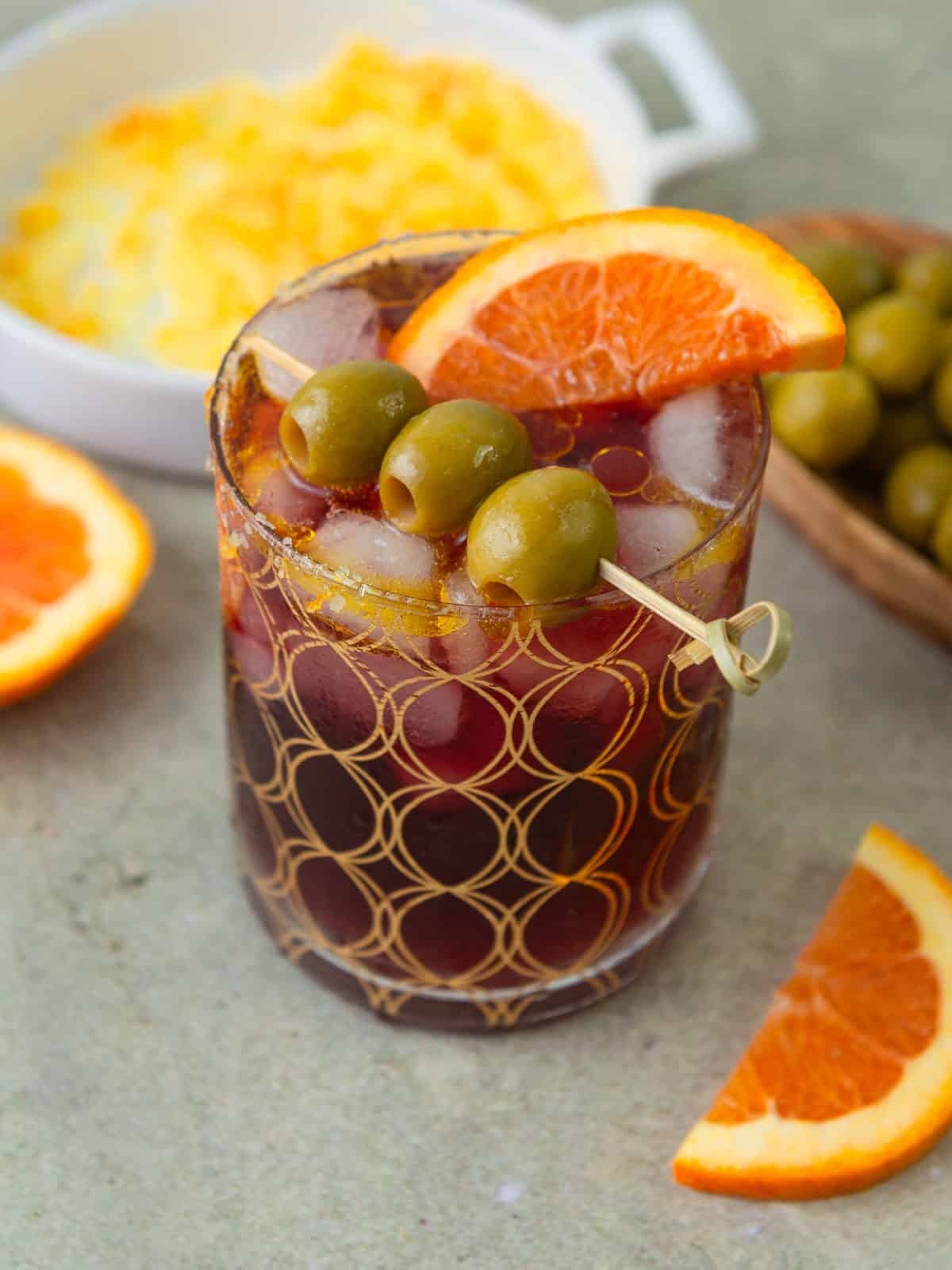 Lambrusco spritz is garnished with olives, olive oil and an orange slice.