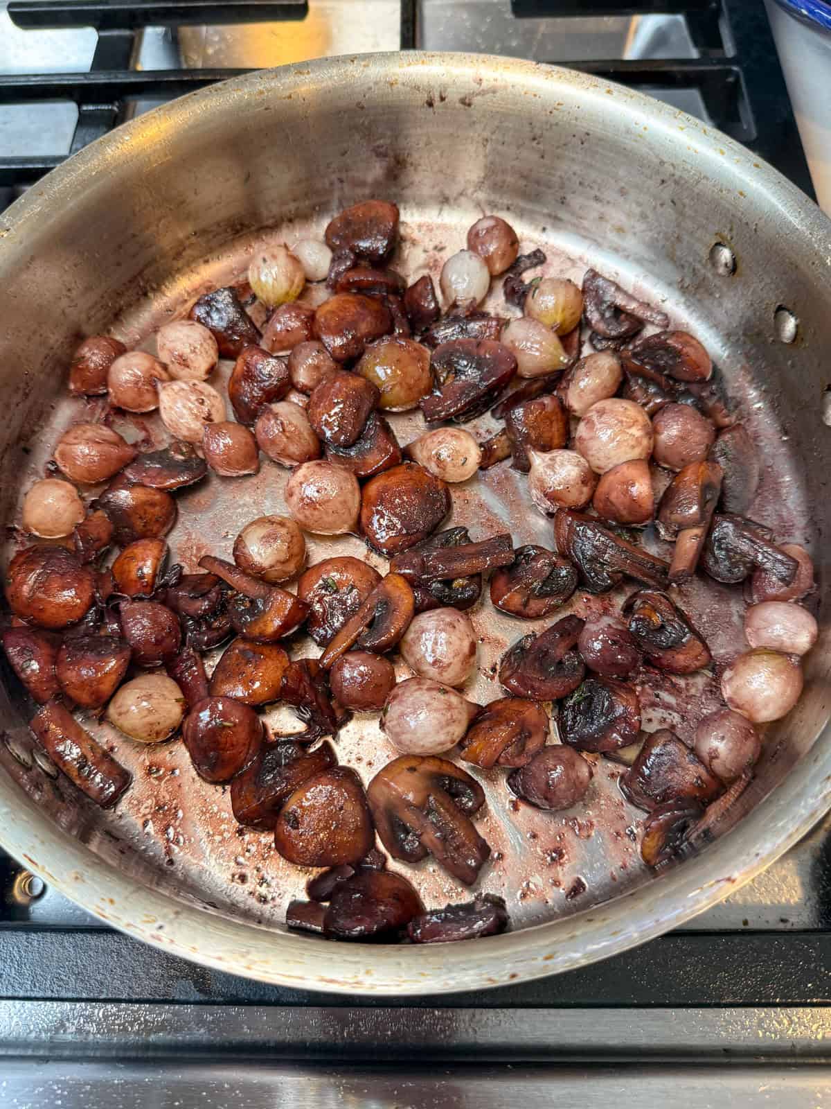 In a separate pan, cook mushrooms and pearl onions in butter and a splash of wine until golden. This adds fresh flavor and texture.