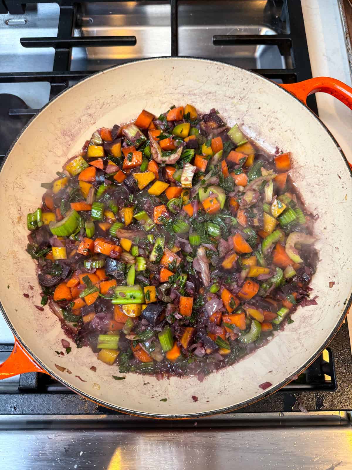 Add red wine to the sautéed vegetables and let the wine reduce.