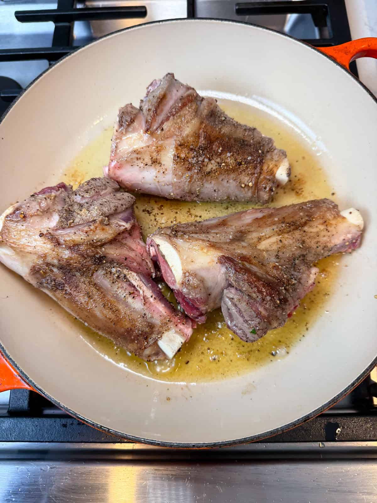 Sear the lamb shanks in olive oil until brown on all sides.