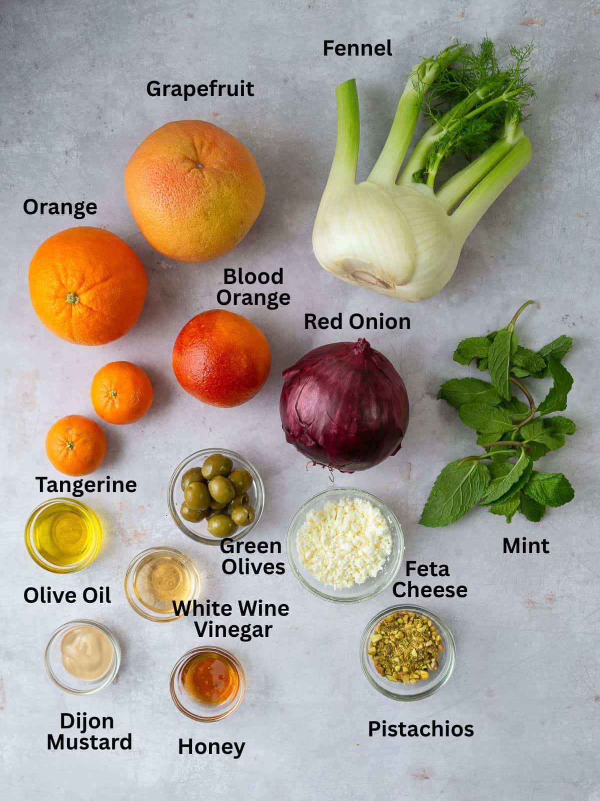 Ingredients for citrus fennel salad with red onion, pistachios, fresh herbs and olives.