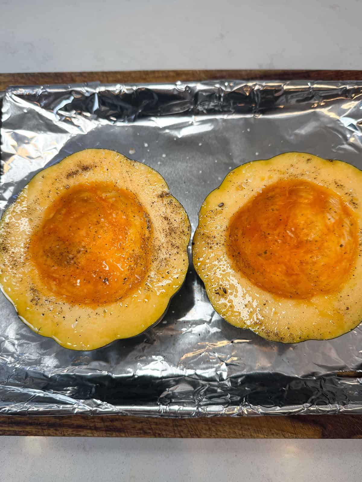 Cut the acorn squash in half, scoop out the seeds and season with olive oil, salt and pepper.