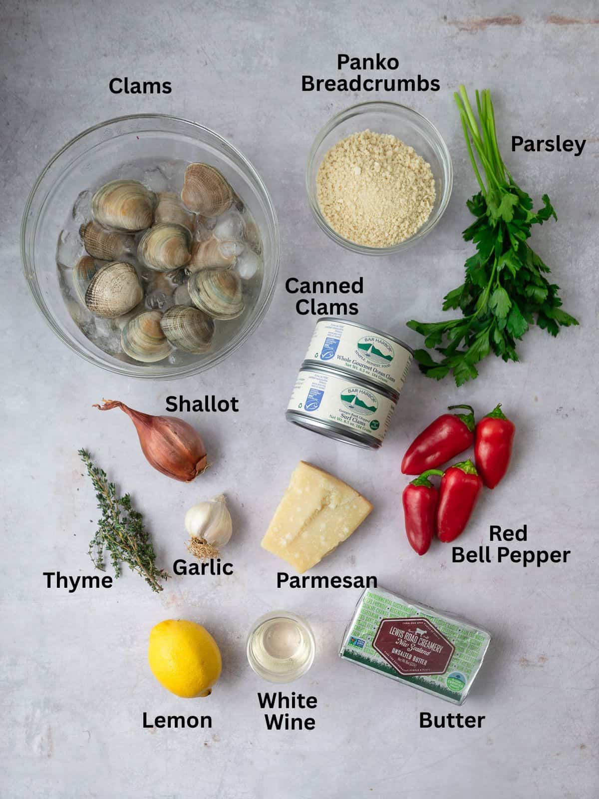 Ingredients for baked clams casino including panko breadcrumbs, canned clams, garlic, shallot, parsley and bell peppers.