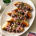 These Middle Eastern stuffed pitas are filled with a flavorful beef mixture and topped with sumac onions, creamy tahini sauce and herbs.